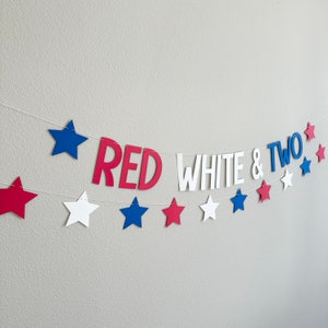 May include: Red, white, and blue paper banner with stars and the words "RED WHITE & TWO" for a birthday party.