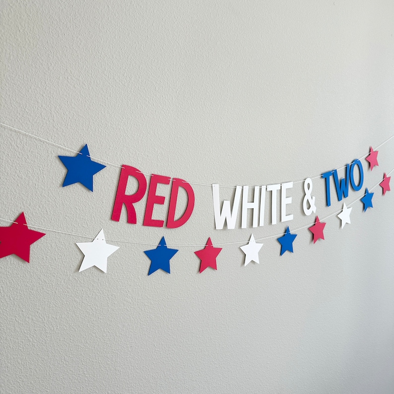 May include: Red, white, and blue paper banner with stars and the words "RED WHITE & TWO" for a birthday party.