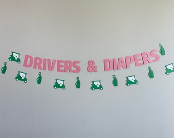 May include: A pink and green paper banner with the text "DRIVERS & DIAPERS" and golf cart and golf club cutouts.