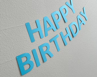 May include: A blue paper banner with the words "Happy Birthday" strung on a white string.