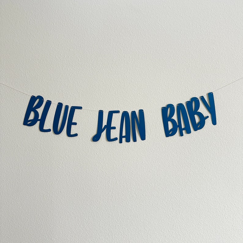 May include: Blue Jean Baby banner with blue letters on a white background.