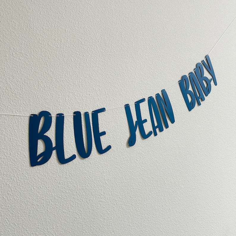 May include: Blue Jean Baby banner with blue letters on a white background.