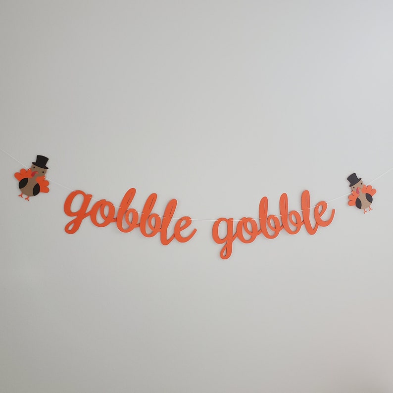 May include: Orange paper banner with the words "gobble gobble" and two turkey cutouts on either end.