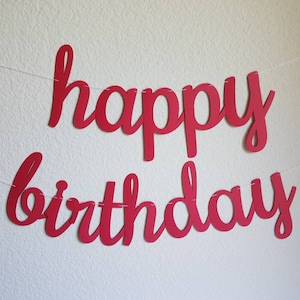 May include: Red paper banner with the words "happy birthday" in a cursive font.