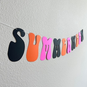 May include: A summer-themed banner with the word "SUMMER" in black, orange, and pink letters. The letters are cut out in a retro, wavy style.