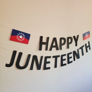 May include: A black banner with the words "Happy Juneteenth" in large, bold letters. The banner is decorated with two small red, white, and blue flags.