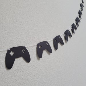 May include: Black paper game controller cutouts strung together on white string to create a party banner.