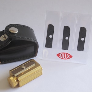 Apontador de lápis DUX BRASS VARIABLE com 3 lâminas sobressalentes.