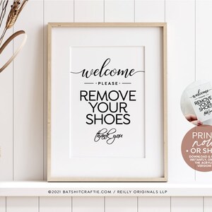 Puede incluir: Un cartel imprimible con el texto "Bienvenido, por favor, quítate los zapatos, gracias" en blanco y negro. El cartel está enmarcado en un marco de madera clara y se exhibe en un estante blanco con un jarrón de trigo seco.