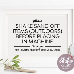 May include: A white framed sign with black text that reads "please. SHAKE SAND OFF ITEMS (OUTDOORS) BEFORE PLACING IN MACHINE thank you. FOR HELPING PREVENT COSTLY DAMAGES"
