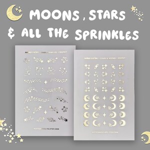 Op de afbeelding: Twee vellen stickers met gouden maan- en sterrenfolie. De tekst "MOONS, STARS & ALL THE SPRINKLES" staat bovenaan. Eén vel heeft sterrenclusters en -sporen, de andere manen en sterren. De website notesandclips.etsy.com staat onderaan.