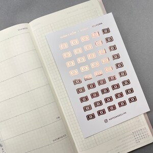 May include: A sheet of stickers with a rose gold and black design of money bills. The sheet is labeled "notes & clips - money - 206RGMN" and has the Instagram handle "@notesandclips" in the bottom right corner.