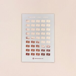 May include: A sheet of 50 rose gold foil stickers featuring a money bill design. The stickers are arranged in rows on a white background. The text "NOTES & CLIPS - MONEY - 206RGMM" is printed at the top of the sheet. The text "@NOTESANDCLIPS" is printed at the bottom of the sheet.