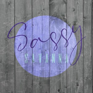 May include: A wooden background with vertical planks in shades of gray. A purple circle in the center contains the words "Sassy Savannah" in a cursive font and a sans-serif font.