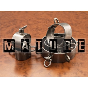 Op de afbeelding: Drie zilveren metalen ringen met een scharniergesp. De ringen zijn op elkaar gestapeld. Het woord "MATURE" is in zwarte letters over de afbeelding gedrukt.