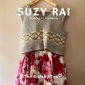 Può includere: Un gilet grigio a maglia con un motivo a rombi color crema e marrone, appeso a una gruccia di legno. Il gilet è abbinato a un vestito con stampa floreale bianca e rossa. Il testo in alto recita "SUZY RAI Hand Knit Patterns" e "The Gatsby Tank" in basso.