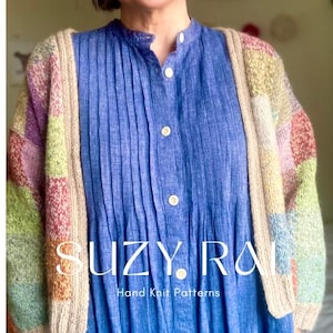 Puede incluir: Un cárdigan de punto multicolor con borde beige se usa sobre un vestido azul abotonado. El cárdigan presenta cuadrados pastel de color rosa, verde, amarillo y morado. El texto "SUZY RAI Hand Knit Patterns" es visible en la parte inferior de la imagen.