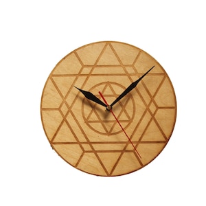 May include: A wooden clock with a geometric design and black hands. The clock face is a light brown colour and the hands are black.