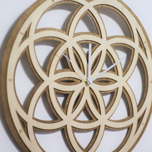 May include: A wooden clock with a geometric design, featuring a light brown wood color and white clock hands.