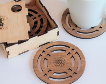 May include: Set of four wooden coasters with a geometric design, featuring a circular pattern with a flower of life symbol in the center. The coasters come in a wooden box with a lid.