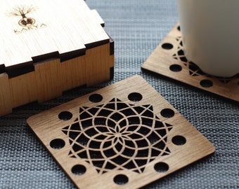 May include: Set of four wooden coasters with a geometric design. The coasters are in a box with the word "Karya" printed on it.