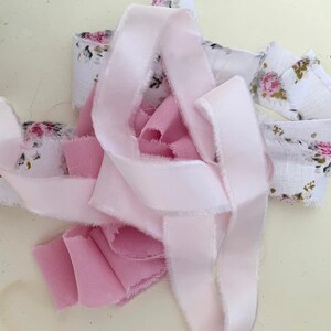 May include: A collection of pink and white fabric scraps with a floral pattern. The fabric is frayed and has a rustic look.
