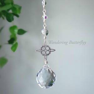 May include: A silver-toned suncatcher with a faceted crystal ball at the bottom. The suncatcher features a Celtic knot design and iridescent beads. The text "Wandering Butterflyy" is visible.