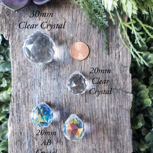 May include: Three crystal balls on a wooden surface. The largest ball is 30mm clear crystal, the middle ball is 20mm clear crystal, and the smallest ball is 20mm AB crystal.