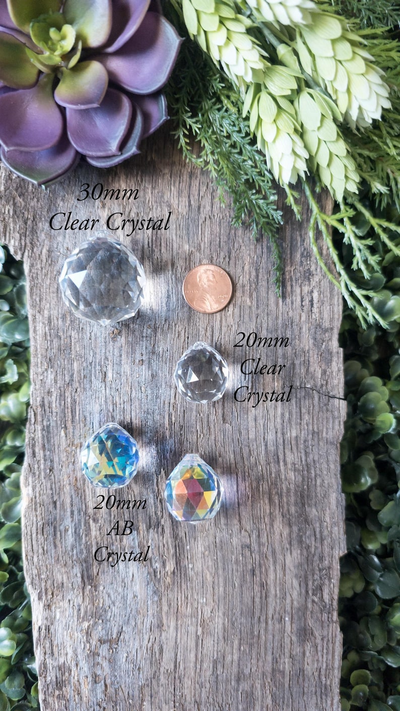 May include: Three crystal balls on a wooden surface. The largest ball is 30mm clear crystal, the middle ball is 20mm clear crystal, and the smallest ball is 20mm AB crystal.