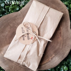 May include: A brown paper parcel tied with twine and a tag that says "Handmade with love". The parcel is sitting on a wooden surface.