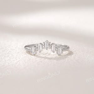 May include: A silver ring with a curved design, featuring rectangular and round-cut gemstones. The ring has a delicate, elegant appearance, with the brand name "RINGONLY" visible at the top.
