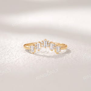 May include: A gold-colored ring with a curved design. The ring features a series of rectangular and round-cut clear stones. The brand name "RINGONLY" is visible at the top of the image. The ring is set against a white background.