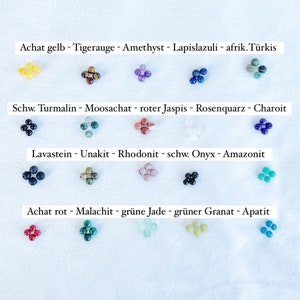 Pu&ograve; includere: Una collezione di 10 diversi tipi di perle di pietre preziose, ciascuna di un colore diverso. Le perle sono disposte in quattro file, con i nomi delle pietre preziose scritti sopra ogni fila. Le pietre preziose sono: Achat gelb, Tigerauge, Amethyst, Lapislazuli, afrik. T&uuml;rkis, Schw. Turmalin, Moosachat, roter Jaspis, Rosenquarz, Charoit, Lavastein, Unakit, Rhodonit, schw. Onyx, Amazonit, Achat rot, Malachit, gr&uuml;ne Jade, gr&uuml;ner Granat, Apatit.