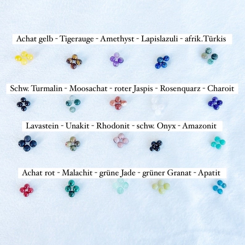 Pu&ograve; includere: Una collezione di 10 diversi tipi di perle di pietre preziose, ciascuna di un colore diverso. Le perle sono disposte in quattro file, con i nomi delle pietre preziose scritti sopra ogni fila. Le pietre preziose sono: Achat gelb, Tigerauge, Amethyst, Lapislazuli, afrik. T&uuml;rkis, Schw. Turmalin, Moosachat, roter Jaspis, Rosenquarz, Charoit, Lavastein, Unakit, Rhodonit, schw. Onyx, Amazonit, Achat rot, Malachit, gr&uuml;ne Jade, gr&uuml;ner Granat, Apatit.