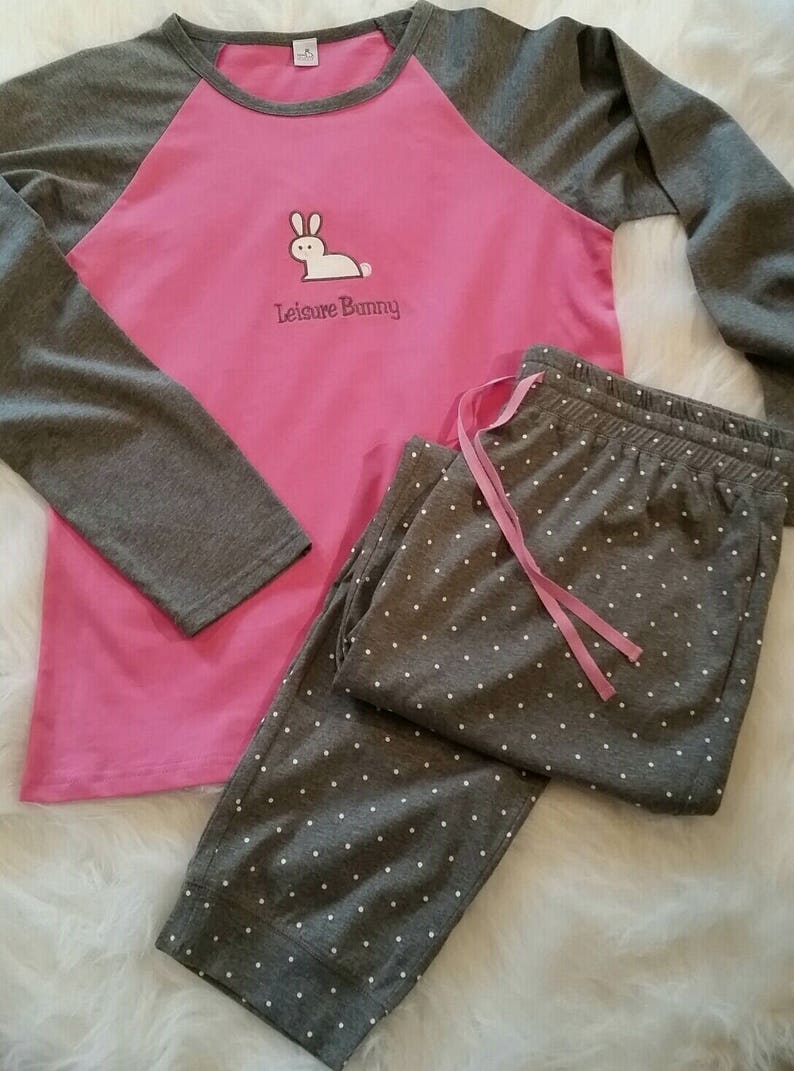 Peut inclure: Un ensemble pyjama rose et gris &agrave; manches longues avec un motif de lapin blanc sur le haut. Le haut est brod&eacute; du texte "Leisure Bunny". Le pantalon a un motif de pois blancs.