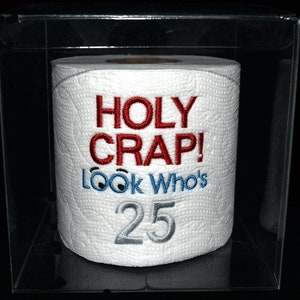 May include: A white toilet paper roll with red and blue embroidery that says "HOLY CRAP! LOOK WHO'S 25". The roll is in a clear plastic box.