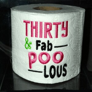 May include: A white toilet paper roll with the text "THIRTY & Fab-POO-LOUS" embroidered in pink and black.