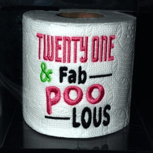 May include: A white toilet paper roll with the text "Twenty One & Fab-Poo-Lous" embroidered in pink, black, and green.