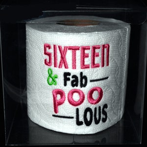 May include: A white toilet paper roll with the text "SIXTEEN & Fab-POO-LOUS" embroidered in pink, green, and black.