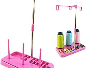 Può includere: Portafilo in plastica rosa con tre bobine e un porta aghi incorporato. Il supporto ha un'asta di metallo con tre ganci nella parte superiore.