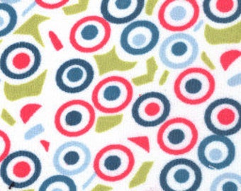 May include: White fabric with a repeating pattern of red, blue, and light blue circles with white centers. The circles are overlapping and some are partially obscured by green shapes.