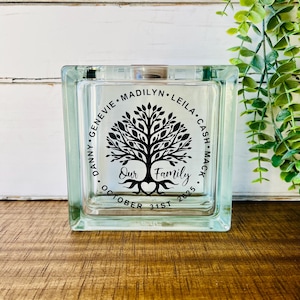 May include: A clear glass block with a black tree design and the text "Our Family" with the names "Danny, Genvie, Madilyn, Leila, Cash, Mack" and the date "October 31st 2025".