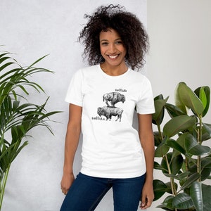 May include: A white t-shirt with a black and white illustration of two buffalo stacked on top of each other. The text "Soft as a Buffalo" is above the buffalo and the text "Buffalo" is below the buffalo.