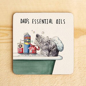 May include: A white coaster with the text "Dad's Essential Oils" and a cartoon illustration of a dog in a bathtub with a can of oil, a bottle of oil, and a red can.