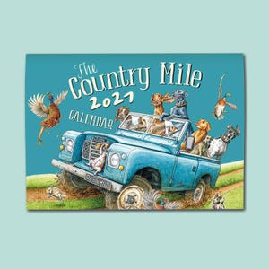 May include: A 2021 calendar titled The Country Mile featuring a blue off-road vehicle driven by various dog breeds, including a black Labrador and a golden retriever, with a pheasant and a duck flying in the sky and a rabbit running on the grass.