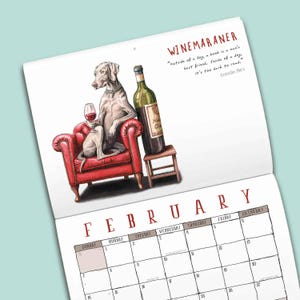 May include: A wall calendar page for February featuring a Weimaraner dog wearing a pearl necklace, sitting in a red tufted armchair holding a wine glass next to a wine bottle on a stool. The text reads WINEMARANER and a quote by Groucho Marx.