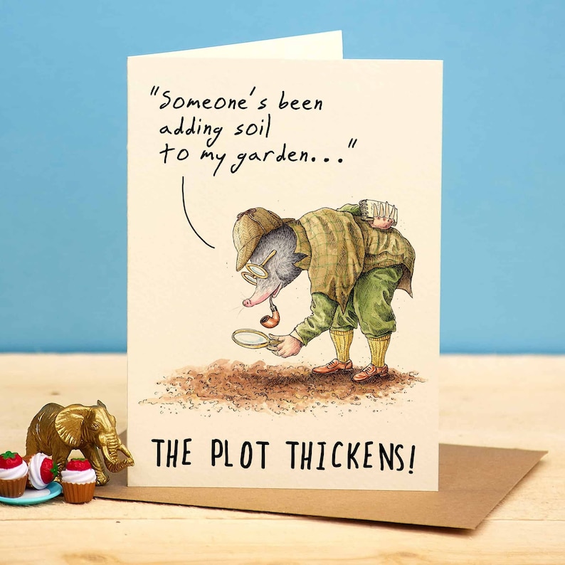 May include: A humorous greeting card featuring a cartoon mole wearing a detective hat and holding a magnifying glass. The text on the card reads "Someone's been adding soil to my garden..." and "The plot thickens!"