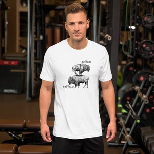 May include: White t-shirt with a black and white illustration of two buffalo stacked on top of each other. The text "Buffalo" is written below the bottom buffalo and the text "Buffalo" is written above the top buffalo.