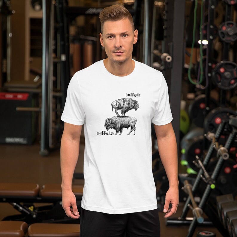 May include: White t-shirt with a black and white illustration of two buffalo stacked on top of each other. The text "Buffalo" is written below the bottom buffalo and the text "Buffalo" is written above the top buffalo.
