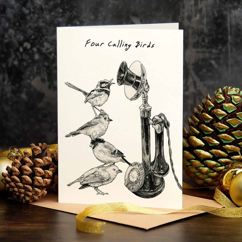 May include: A white card with black ink reads "Four Calling Birds".  The card features a black and white illustration of four birds perched on an old-fashioned rotary phone.